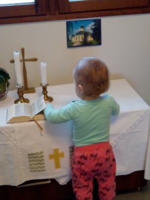 Kuva lapsesta Pikku-Pappilan pikkukirkossa alttaripöydän ääressä tutkimassa Raamattua.