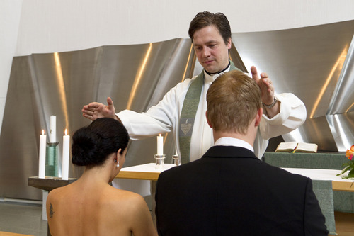 Kuvalinkki Hyrynsalmen seurakunnan hääalasivulle. Kuvassa pappi siunaa avioparia.